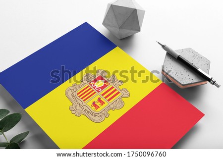 Andorra flag on minimalist paper background. National invitation letter with stylish pen on stone. Communication concept.