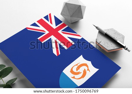 Anguilla flag on minimalist paper background. National invitation letter with stylish pen on stone. Communication concept.