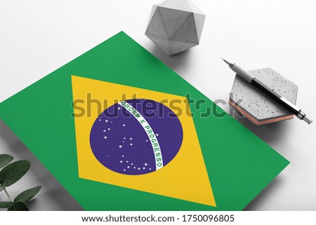 Brazil flag on minimalist paper background. National invitation letter with stylish pen on stone. Communication concept.