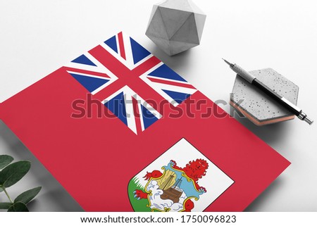 Bermuda flag on minimalist paper background. National invitation letter with stylish pen on stone. Communication concept.