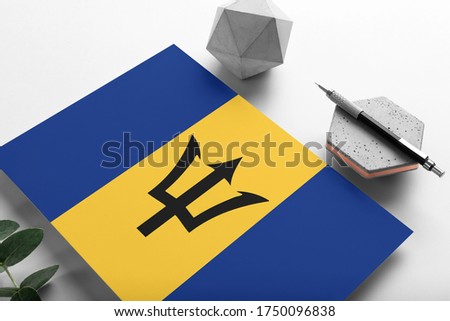 Barbados flag on minimalist paper background. National invitation letter with stylish pen on stone. Communication concept.