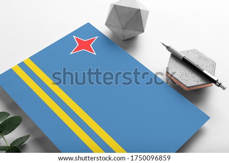 Aruba flag on minimalist paper background. National invitation letter with stylish pen on stone. Communication concept.