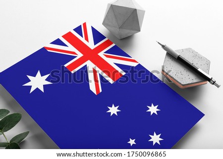 Australia flag on minimalist paper background. National invitation letter with stylish pen on stone. Communication concept.