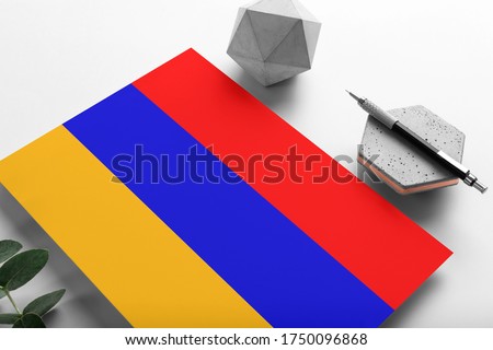 Armenia flag on minimalist paper background. National invitation letter with stylish pen on stone. Communication concept.