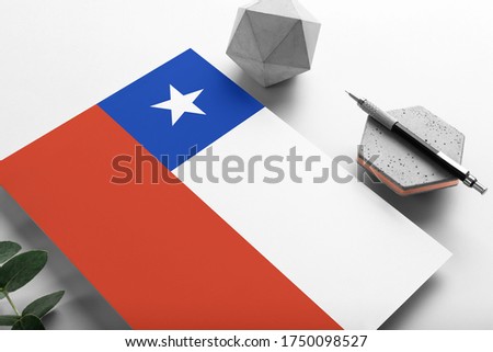 Chile flag on minimalist paper background. National invitation letter with stylish pen on stone. Communication concept.