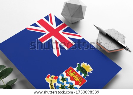Cayman Islands flag on minimalist paper background. National invitation letter with stylish pen on stone. Communication concept.