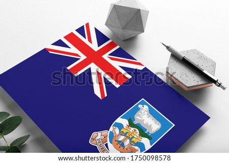 Falkland Islands flag on minimalist paper background. National invitation letter with stylish pen on stone. Communication concept.