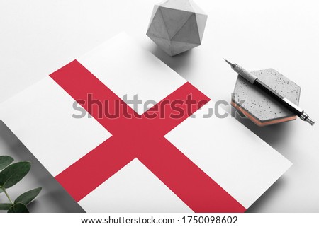 England flag on minimalist paper background. National invitation letter with stylish pen on stone. Communication concept.