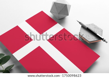 Denmark flag on minimalist paper background. National invitation letter with stylish pen on stone. Communication concept.