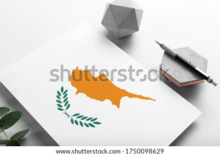 Cyprus flag on minimalist paper background. National invitation letter with stylish pen on stone. Communication concept.