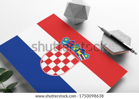 Croatia flag on minimalist paper background. National invitation letter with stylish pen on stone. Communication concept.