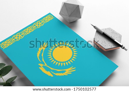 Kazakhstan flag on minimalist paper background. National invitation letter with stylish pen on stone. Communication concept.