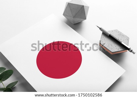 Japan flag on minimalist paper background. National invitation letter with stylish pen on stone. Communication concept.