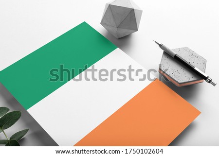 Ireland flag on minimalist paper background. National invitation letter with stylish pen on stone. Communication concept.