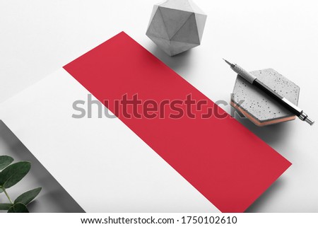 Indonesia flag on minimalist paper background. National invitation letter with stylish pen on stone. Communication concept.