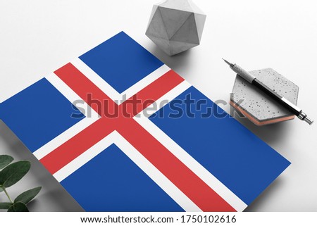 Iceland flag on minimalist paper background. National invitation letter with stylish pen on stone. Communication concept.