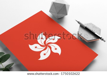 Hong Kong flag on minimalist paper background. National invitation letter with stylish pen on stone. Communication concept.