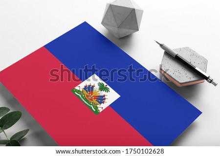 Haiti flag on minimalist paper background. National invitation letter with stylish pen on stone. Communication concept.