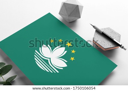Macao flag on minimalist paper background. National invitation letter with stylish pen on stone. Communication concept.