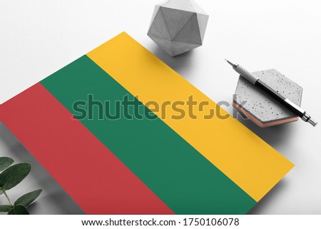 Lithuania flag on minimalist paper background. National invitation letter with stylish pen on stone. Communication concept.