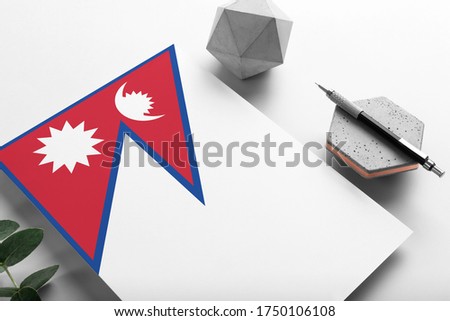 Nepal flag on minimalist paper background. National invitation letter with stylish pen on stone. Communication concept.