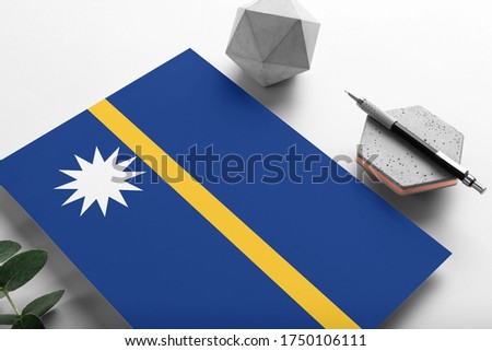 Nauru flag on minimalist paper background. National invitation letter with stylish pen on stone. Communication concept.