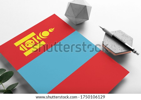 Mongolia flag on minimalist paper background. National invitation letter with stylish pen on stone. Communication concept.