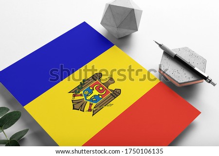 Moldova flag on minimalist paper background. National invitation letter with stylish pen on stone. Communication concept.