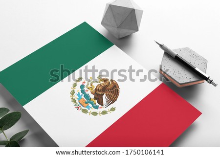 Mexico flag on minimalist paper background. National invitation letter with stylish pen on stone. Communication concept.