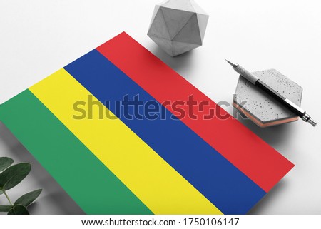 Mauritius flag on minimalist paper background. National invitation letter with stylish pen on stone. Communication concept.