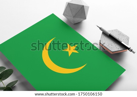 Mauritania flag on minimalist paper background. National invitation letter with stylish pen on stone. Communication concept.