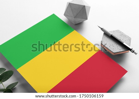 Mali flag on minimalist paper background. National invitation letter with stylish pen on stone. Communication concept.