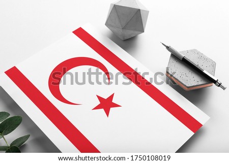 Northern Cyprus flag on minimalist paper background. National invitation letter with stylish pen on stone. Communication concept.