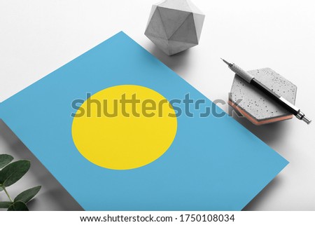 Palau flag on minimalist paper background. National invitation letter with stylish pen on stone. Communication concept.