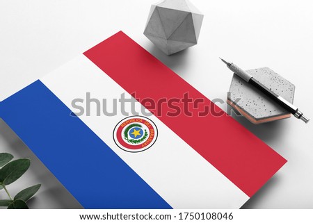 Paraguay flag on minimalist paper background. National invitation letter with stylish pen on stone. Communication concept.