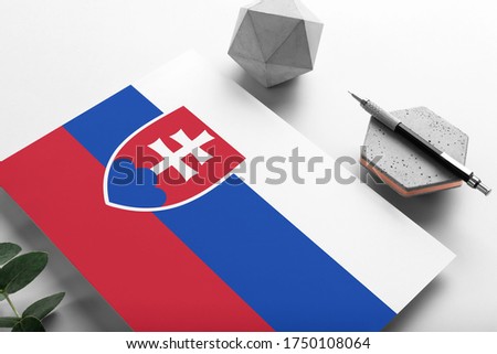 Slovakia flag on minimalist paper background. National invitation letter with stylish pen on stone. Communication concept.