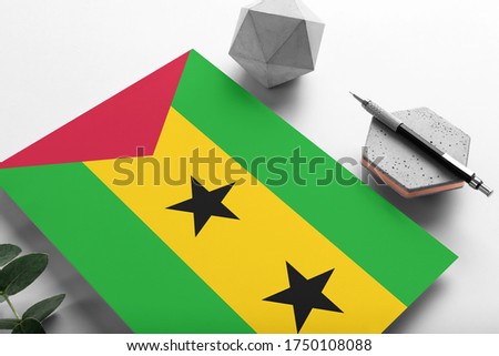 Sao Tome And Principe flag on minimalist paper background. National invitation letter with stylish pen on stone. Communication concept.