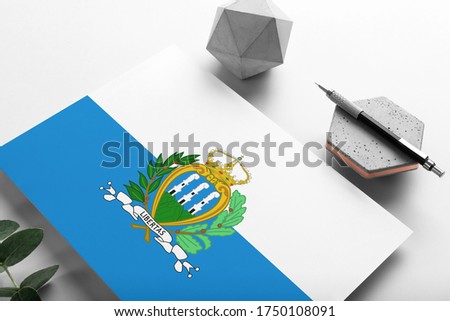 San Marino flag on minimalist paper background. National invitation letter with stylish pen on stone. Communication concept.