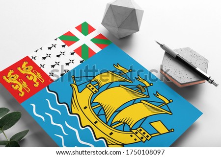 Saint Pierre And Miquelon flag on minimalist paper background. National invitation letter with stylish pen on stone. Communication concept.
