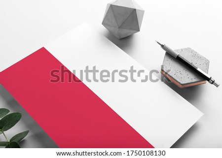 Poland flag on minimalist paper background. National invitation letter with stylish pen on stone. Communication concept.