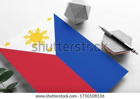 Philippines flag on minimalist paper background. National invitation letter with stylish pen on stone. Communication concept.