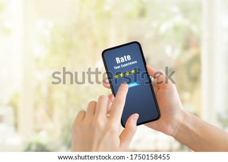 Customer Feedback Concept : Hand pressing feedback button on smartphone for giving best service ranking with blurred cafe restaurant or coffee shop in background.