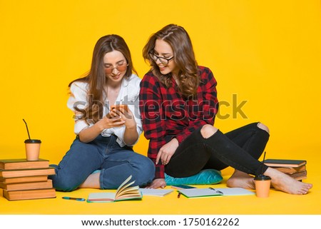 Two Happiness  smiling young woman gamer using smart mobile phone and playing games on isolated yellow color background, Lifestyle and leisure with hobby concept
