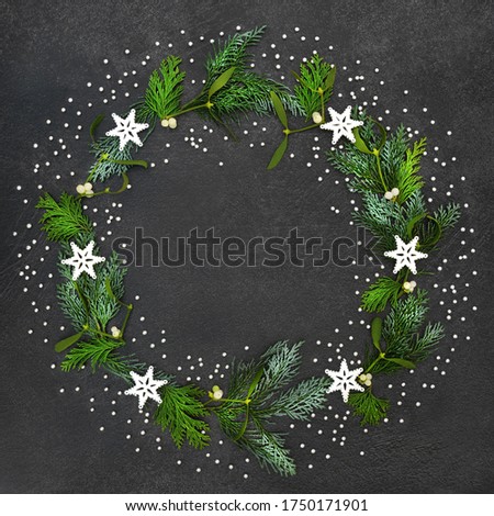 Festive Christmas wreath with stars & decorative silver balls with cedar cypress fir leaves & winter mistletoe on grey grunge background. Xmas & New Year abstract theme.