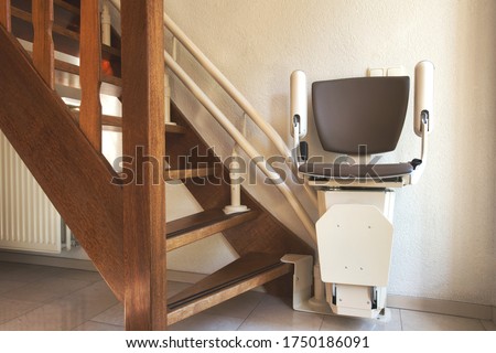 Automatic stairlift on staircase for elderly or disability in a house, taking people up and down Royalty-Free Stock Photo #1750186091