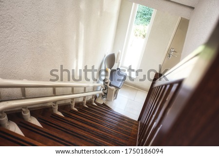 Automatic stairlift on staircase for elderly or disability in a house, taking people up and down Royalty-Free Stock Photo #1750186094