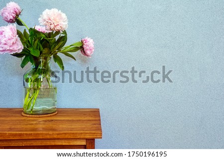 Pink peonies in glass vase on wooden table, romantic design with space for text modern interior beauty