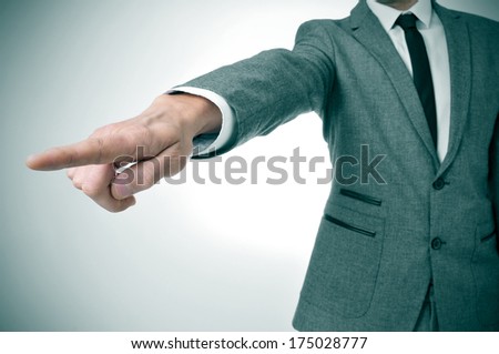 a man wearing a suit pointing with the finger the way out