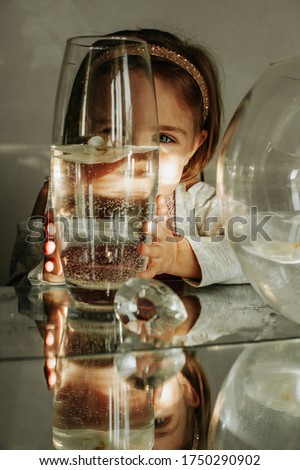 little girl against the backdrop of transparent vases filled with water and flowers. Mirroring in the mirror. Image distortion mirror. good light. bright pictures.