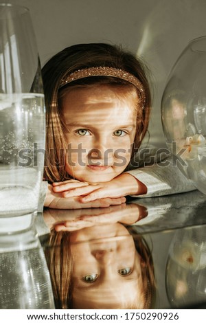 little girl against the backdrop of transparent vases filled with water and flowers. Mirroring in the mirror. Image distortion mirror. good light. bright pictures.